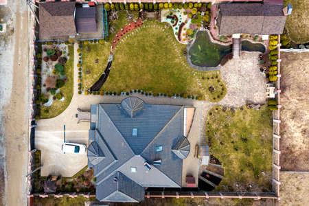 Aerial view of beautifully landscaped property complex. Roofs of recreation house cottage, pond in...