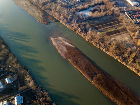 Aerial top view, countryside panorama of small island with dry grass in quiet river on sunny day....