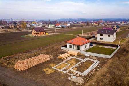 Aerial view of new house roof with attic windows and building site, foundation of future house,...