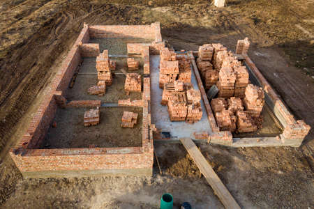 Aerial view of building site. Trenches dug in ground and filled with cement as foundation for future house, brick basement floor and stacks of brick for construction.の写真素材