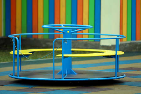 Beautiful playground in kindergarten with soft pavement, bright swings, roundabout and bench on...