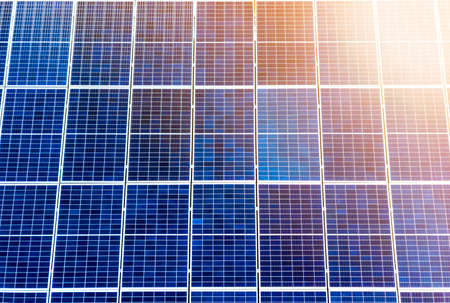 Close-up surface of lit by sun blue shiny solar photo voltaic panels. System producing renewable clean energy. Renewable ecological green energy production concept.の写真素材