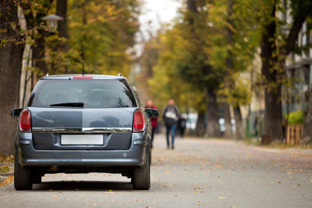 Gray shiny car parked in quiet area on asphalt road on blurred bokeh background on bright sunny day. Transportation and parking concept.の写真素材