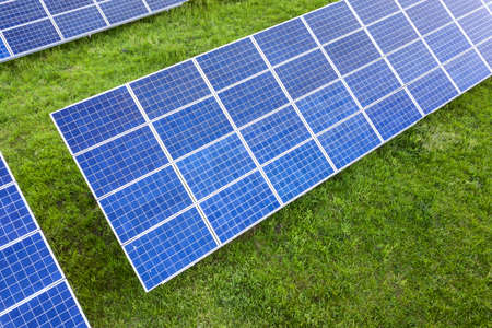 Surface of solar photo voltaic panels system producing renewable clean energy on green grass...