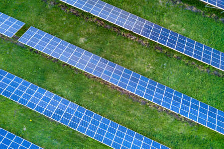Surface of solar photo voltaic panels system producing renewable clean energy on green grass background.の写真素材