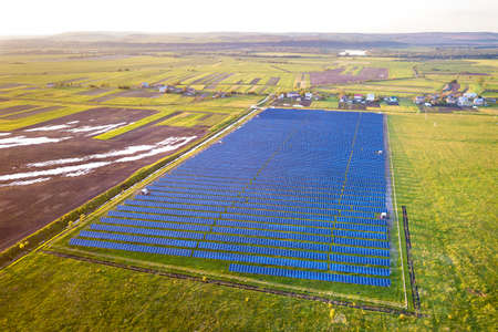 Large field of solar photo voltaic panels system producing renewable clean energy on green grass...