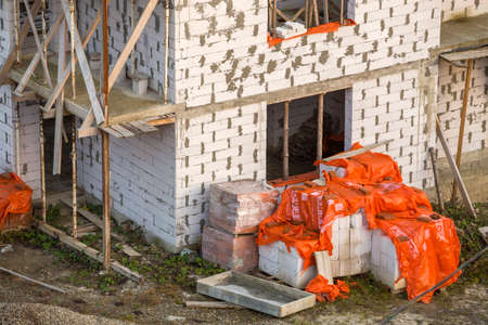 Building under construction. Roof beams frame and roofing underlayment, water-resistant waterproof barrier on walls of hollow foam insulation blocks. Masonry, roofing and renovation.のeditorial素材