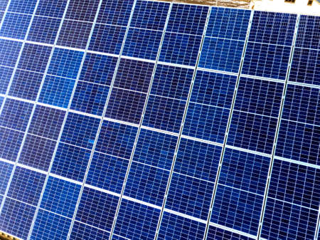 Close-up surface of lit by sun blue shiny solar photo voltaic panels. System producing renewable...