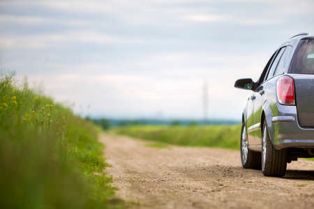 A car on dirt road in green field.