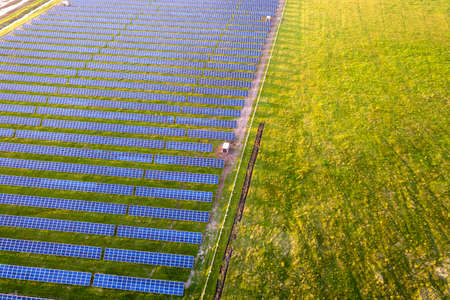 Large field of solar photo voltaic panels system producing renewable clean energy on green grass background.の写真素材