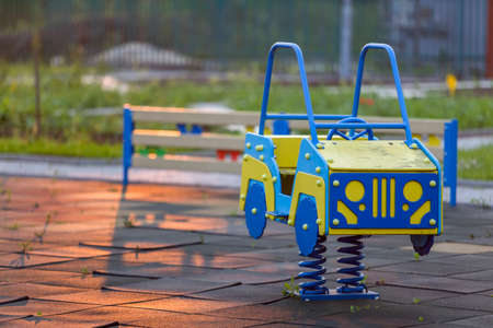 Kindergarten playground with bright toy car on spring. Children activities and recreation outdoors.