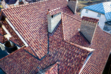 Aerial top view of complex house metal shingle roof and high brick chimneys. Roofing, construction,...