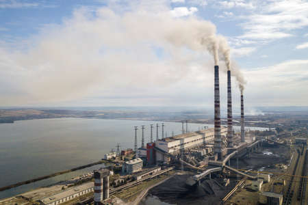 Tall pipes of power plant, white smoke on rural landscape, lake water and blue sky copy space...