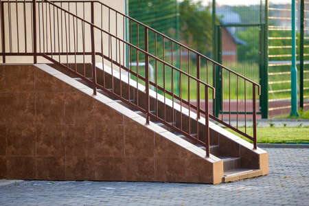 Concrete stairs covered with ceramic tiles with metal railings outdoors.