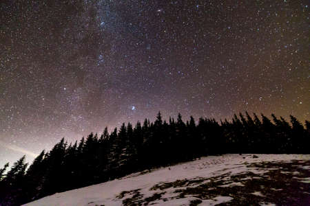 Winter mountains night landscape panorama. Milky Way bright constellation in dark blue starry sky...
