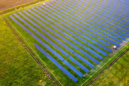 Large field of solar photo voltaic panels system producing renewable clean energy on green grass background.の写真素材