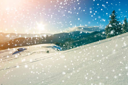 Winter Christmas landscape of mountain valley on frosty sunny day. Old wooden forsaken shepherd hut in white deep clean snow, woody dark mountain ridge, bright sun on blue sky copy space background.の写真素材