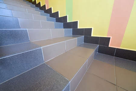 Wide staicase covered with ceramic tiles indoors in a house interior.