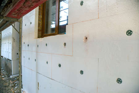 Insulation work of house walls with white foam sheets.