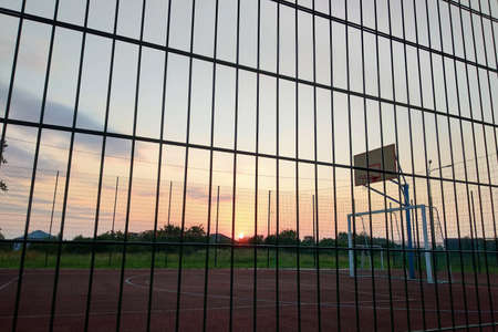Outdoors mini football and basketball court with ball gate and basket surrounded with high protective fence.の写真素材