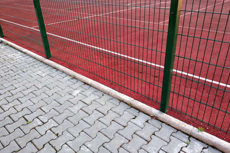 Close-up of white marking lines of outdoor basketball court fenced with protective metal fence.の写真素材