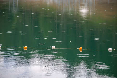 Rope with white and yellow restriction markers on water surface for prohibiting of swimming in deep...