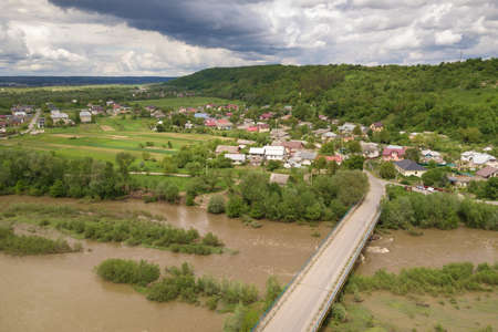 Top down aerial view of town or village with rows of buildings and curvy streets between green fields in summer. Countryside landscape from above.の写真素材