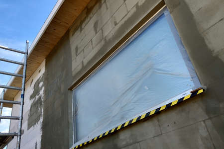 Window of a house under construction covered with protective plastic film.