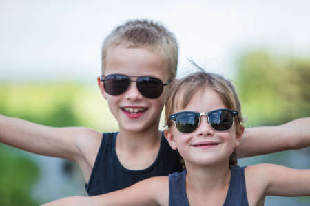Two children in black sunglasses having fun time outdoors in summer.の写真素材