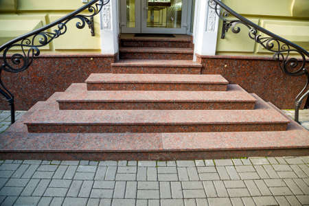 Detail of a house facade. New granite stairs with metal railings.