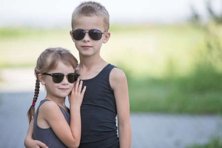 Two children in black sunglasses having fun time outdoors in summer.の写真素材