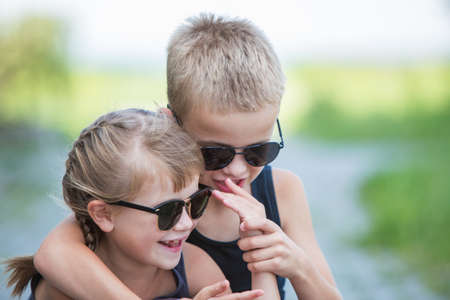 Two children in black sunglasses having fun time outdoors in summer.の写真素材