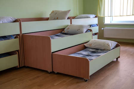 Many small beds in daycare preeschool empty bedroom.