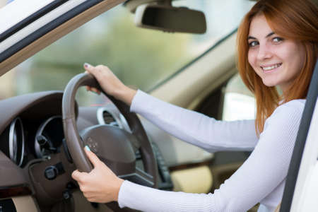 Young woman with red hair driving a car.