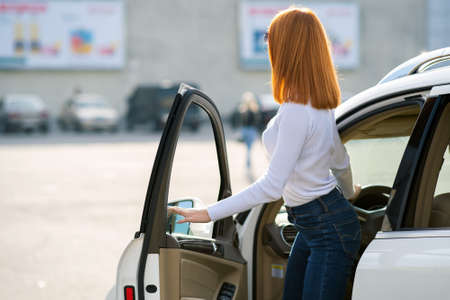 Yong pretty woman standing near a big all terrain car outdoors. Driver girl in casual clothes outside her vehicle.の写真素材