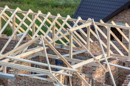 Unfinished brick house with wooden roof structure under construction.の写真素材