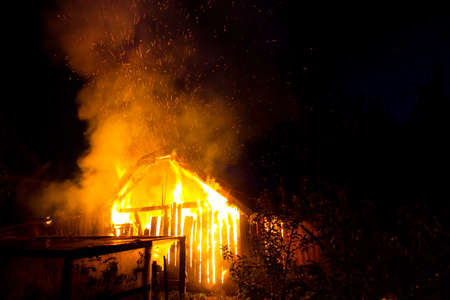 Wooden house or barn burning on fire at night.