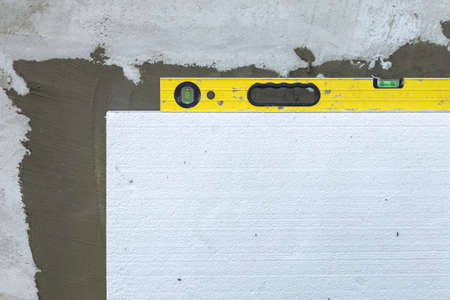Insulation of facade wall with foam sheets. Polystyrene insulation boards with glue adhesive.