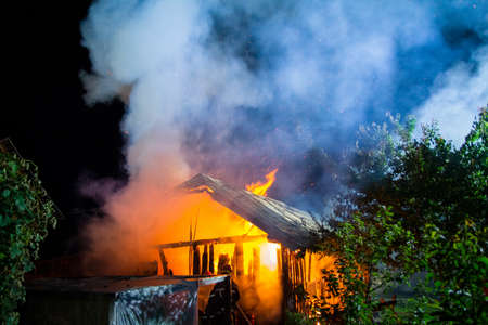 Wooden house or barn burning on fire at night.