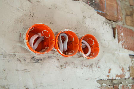 Socket orange boxes with wires in a wall. Cabling installation of electrical wires sticking out from...