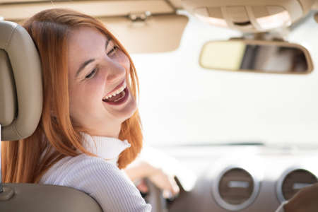 Young redhead woman driver driving a car smiling happily.の写真素材
