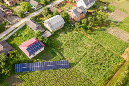 Aerial view of a house with blue solar panels for clean energy.