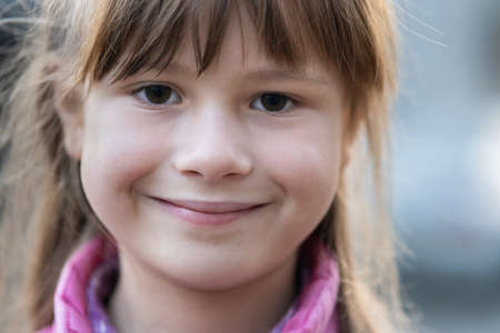 Portrait of happy child girl in warm clothes in autumn outdoors.