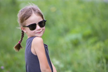 Portrait of pretty child girl with braids in hair outdoors in summer.