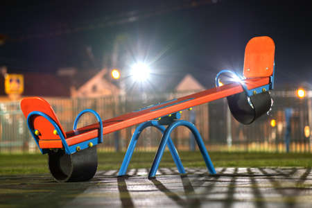 Seesaw swing in preschool yard with soft rubber flooring at night.の写真素材