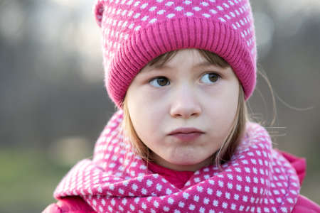 Pretty child girl in warm knitted winter clothes outdoors.の写真素材