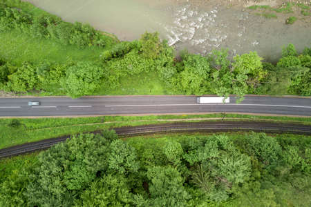 Top down aerial view of winding forest road in green mountain spruce woods.の写真素材
