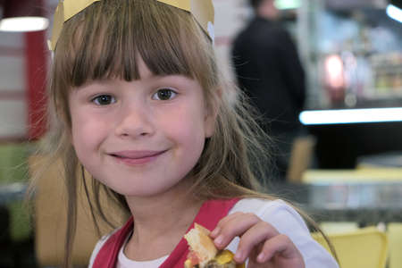 Child girl eating fast food in a restaurant.の写真素材