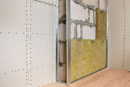 Wall of a room under renovation with mineral rock wool insulation and metal frame prepared for drywall plates.の写真素材