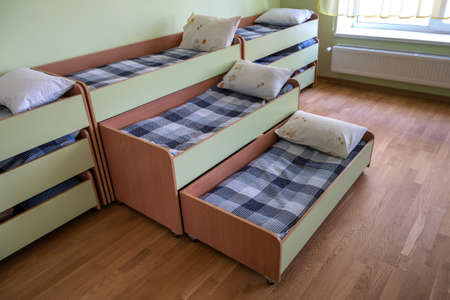 Many small beds in daycare preeschool empty bedroom.